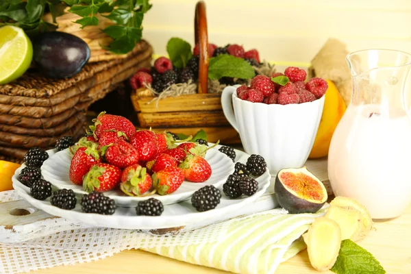 Assortment of juicy fruits and berries on wooden table, on light background — Stock Photo, Image