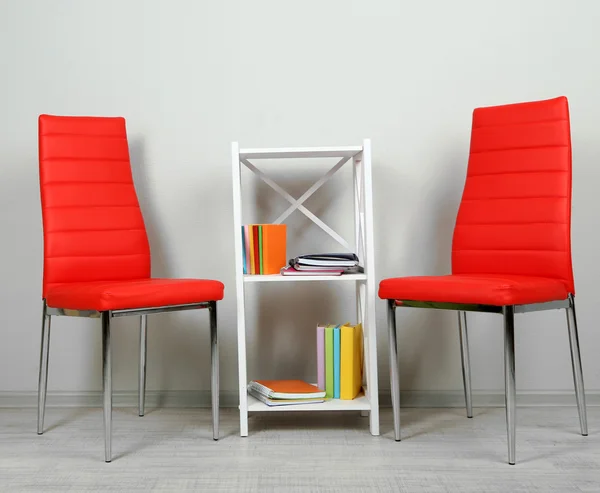 Hermoso interior con sillas de color modernas, libros sobre soporte de madera, sobre fondo de pared —  Fotos de Stock