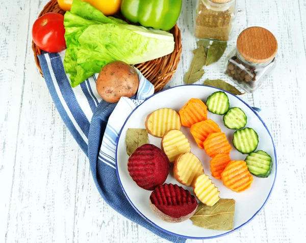 Beautiful sliced vegetables, on plate, on wooden background — Stock Photo, Image