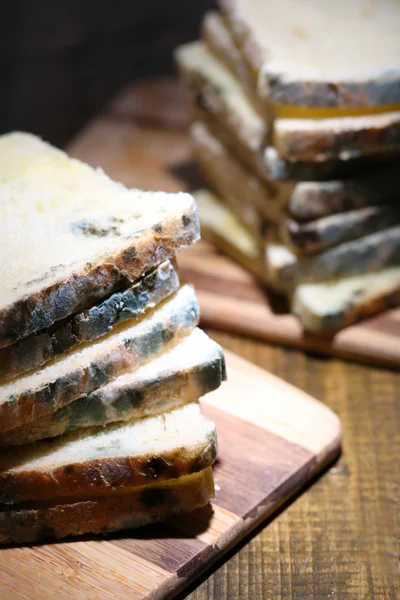 Mögligt bröd på skärbräda, på trä bakgrund — Stockfoto