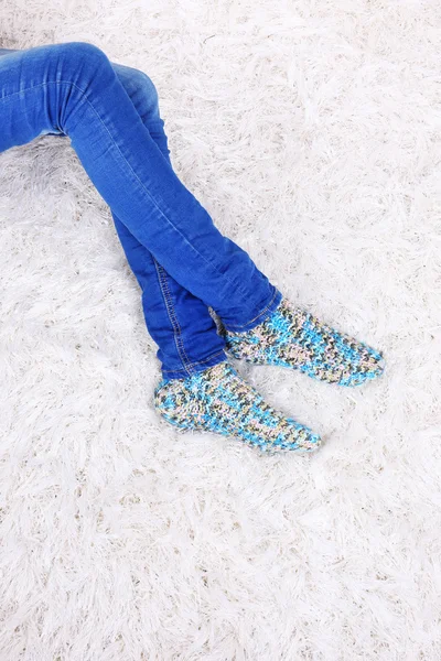 Pernas femininas em calças jeans azuis e meias coloridas no fundo do tapete branco — Fotografia de Stock
