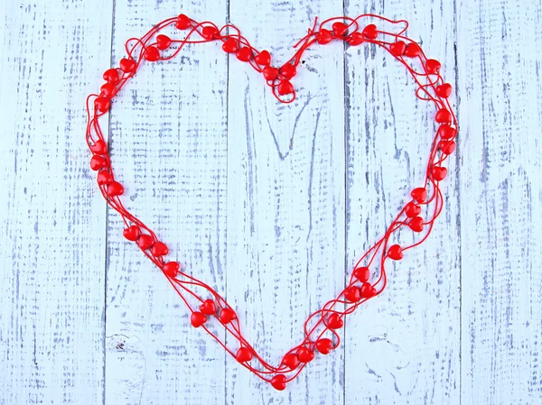 Heart-shaped beads on string on wooden background — Stock Photo, Image