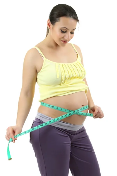 Молодая беременная женщина измеряет ее живот изолирован на белом Лицензионные Стоковые Фото