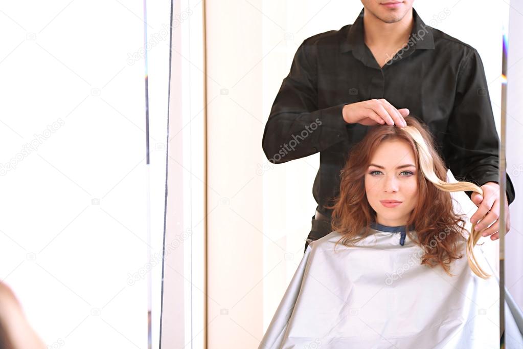Young man hairdresser dyes hair girl in beauty salon