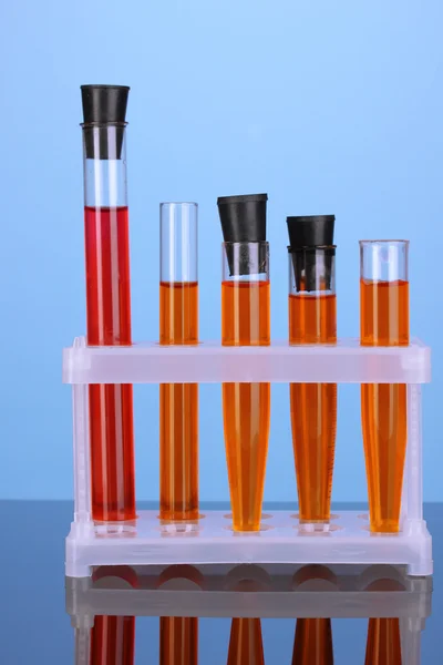 Reagenzgläser mit bunter Lösung auf blauem Hintergrund Nahaufnahme — Stockfoto