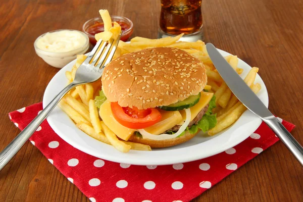 Hambúrguer de queijo saboroso com batatas fritas, em fundo brilhante — Fotografia de Stock