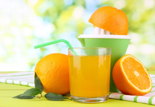 Prensa cítrica, vaso de jugo y naranjas maduras sobre mesa de madera blanca — Foto de Stock