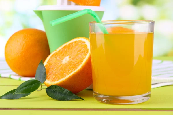 Verre de jus, presse agrumes et orange mûre sur table en bois vert — Photo