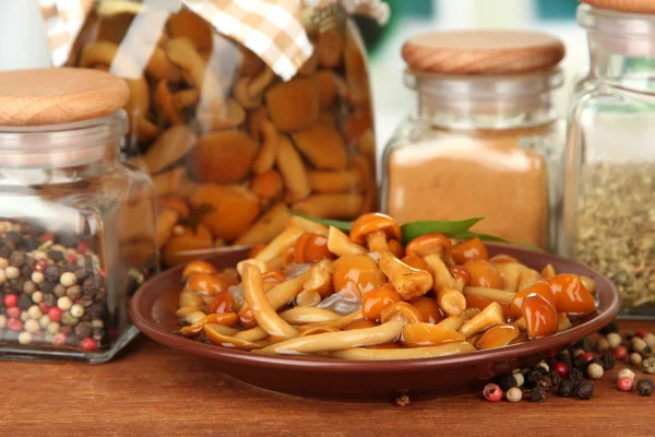 Composizione di deliziosi funghi marinati, olio e spezie su tavolo di legno su sfondo brillante — Foto Stock