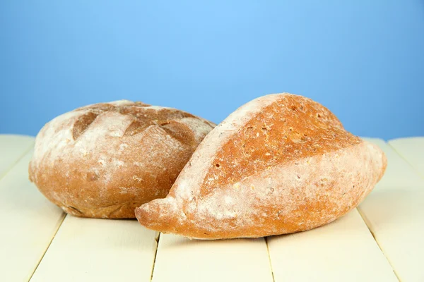 Composition with bread on wooden table, on color background — Stock Photo, Image