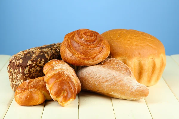 Composition with bread and rolls on wooden table, on color background — Stock Photo, Image