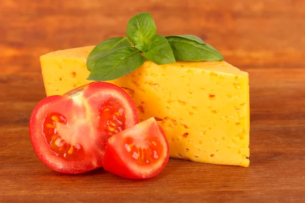Sýrem, bazalkou a rajčaty na dřevěné pozadí — Stock fotografie