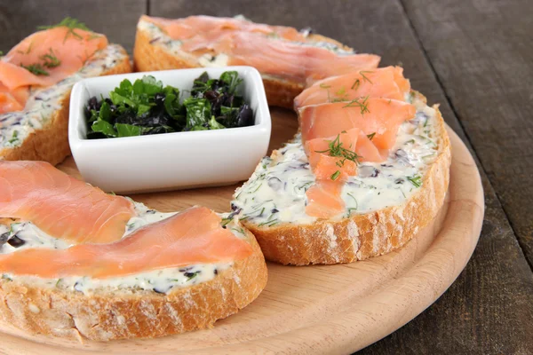 Sandwiches de pescado sobre tabla de cortar sobre mesa de madera — Foto de Stock