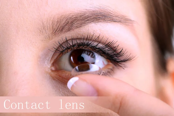 Mladá žena uvedení kontaktní čočky v oku zblízka — Stock fotografie