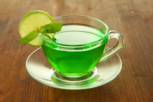Transparent cup of green tea with lime and mint on wooden background — Stock Photo, Image