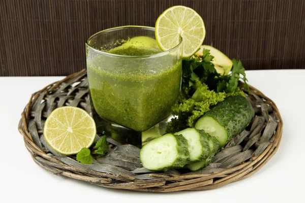 Copo de suco de legumes verde e pepino na mesa no fundo de bambu — Fotografia de Stock
