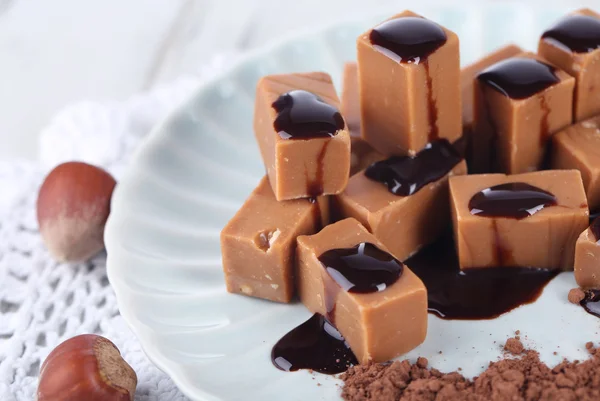 Many toffee on plate on napkin on wooden table — Stock Photo, Image