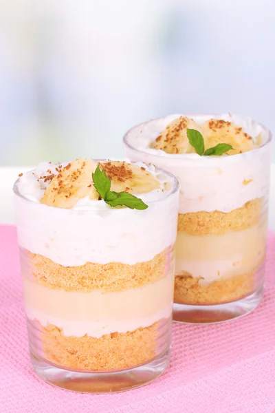 Delicioso postre con plátano y caramelo sobre mesa sobre fondo claro — Foto de Stock