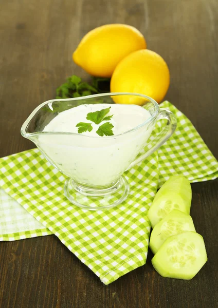 Yogurt al cetriolo in ciotola di vetro, su tovagliolo di colore, su sfondo di legno — Foto Stock