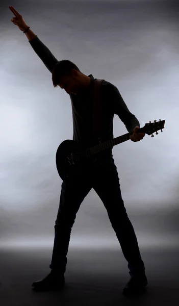 Silhouette guitariste sur fond gris foncé — Photo