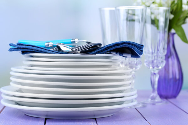 Clean dishes on wooden table on light background