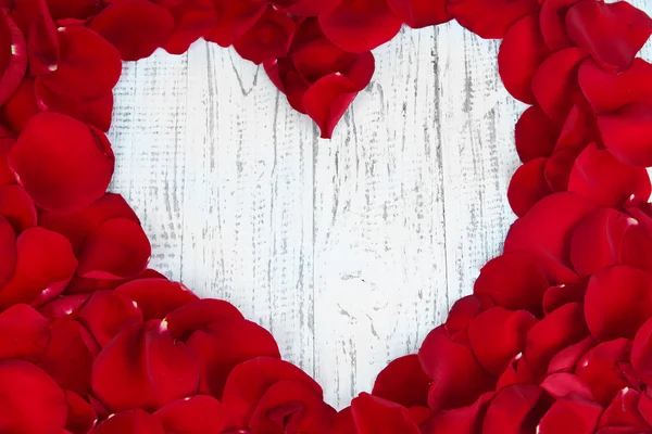 Красивое сердце из красных лепестков роз на деревянном столе крупным планом — стоковое фото