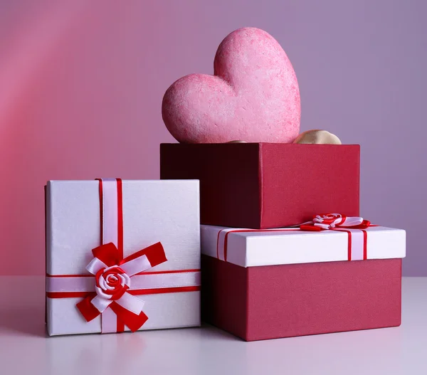 Pilha de caixas de presente e coração decorativo, em fundo de cor — Fotografia de Stock
