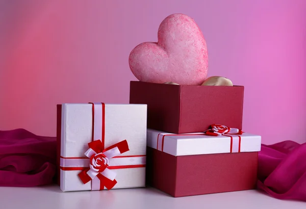 Pila di scatole regalo e cuore decorativo, su sfondo a colori — Foto Stock