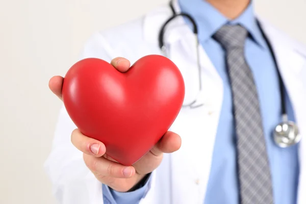 Manliga läkare med rött hjärta i sin hand, isolerad på vit bakgrund — Stockfoto