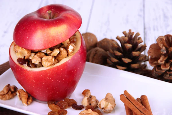 Stuffed apple with nuts and cinnamon on plate on wooden background — Stock Photo, Image