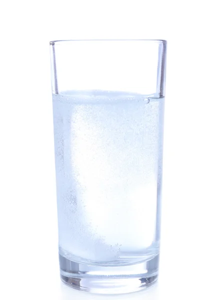 Vidrio con tableta efervescente en agua con burbujas aisladas en blanco — Foto de Stock