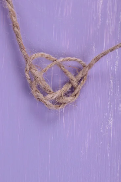 Herzform aus Seil, auf farbigem Holzgrund — Stockfoto