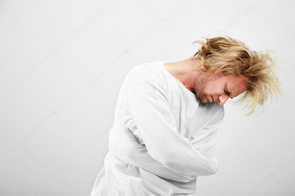 Mentally ill man in strait-jacket on gray background