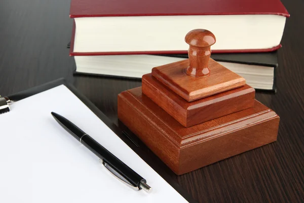 Wooden stamp with clipboard and books on table — Stock Photo, Image