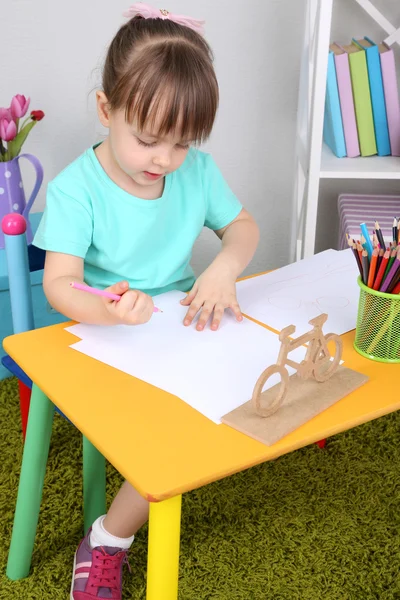 Niña dibuja sentado en la mesa en la habitación —  Fotos de Stock