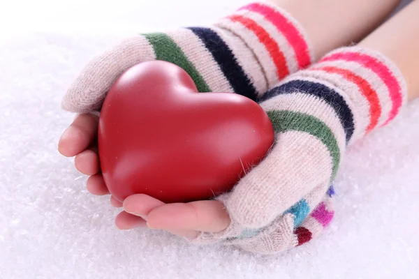 Руки женщины в варежках с сердцем на фоне снега — стоковое фото