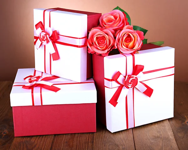 Caixas de presente bonitas com flores na mesa sobre fundo marrom — Fotografia de Stock