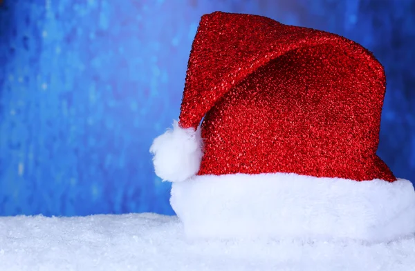 파란색 배경에 눈에 산타 모자 — 스톡 사진