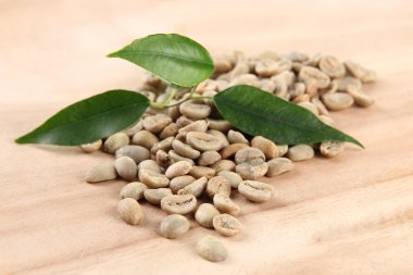 Yeşil kahve çekirdekleri ve ahşap arka plan yapraklarda