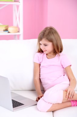 oturma odasındaki kanepe üstünde laptop ile küçük kız