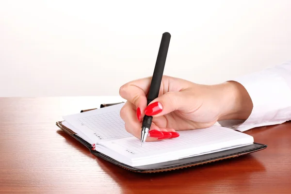 Hand signing in notebook on wooden table isolated on white — Stock Photo, Image