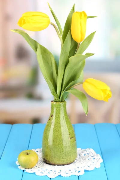 Tulipanes amarillos en jarrón sobre mesa de madera sobre fondo de habitación — Foto de Stock