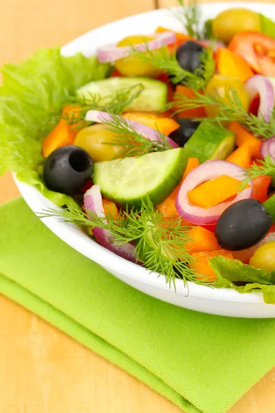 Frischer Salat im Teller auf Holztisch — Stockfoto