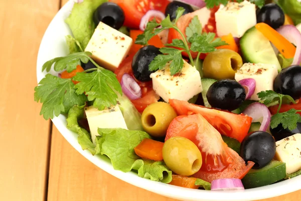 Salade fraîche dans une assiette sur une table en bois — Photo