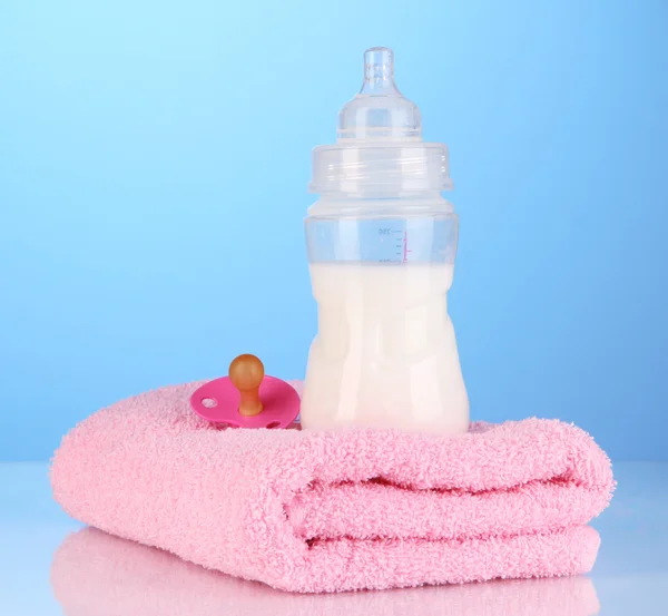 Bottiglia per latte con asciugamani e capezzolo su sfondo blu — Foto Stock