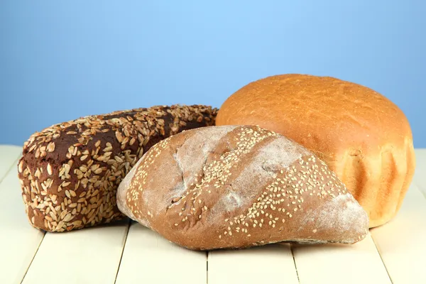 Composition with bread on wooden table, on color background — Stock Photo, Image