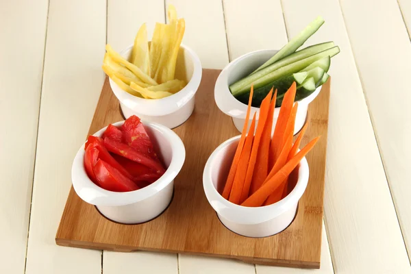 Bright fresh vegetables cut up slices in bowls on wooden table close-up — Stock Photo, Image