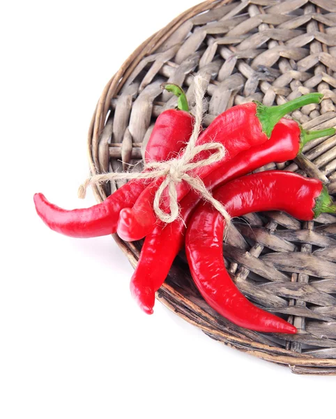 Red hot chili peppers on wicker mat, isolated on white — Stock Photo, Image