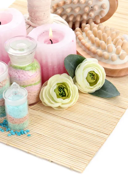 Aromatic salts in glass bottles and herbal compress balls for spa treatment, on bamboo mat, isolated on white — Stock Photo, Image