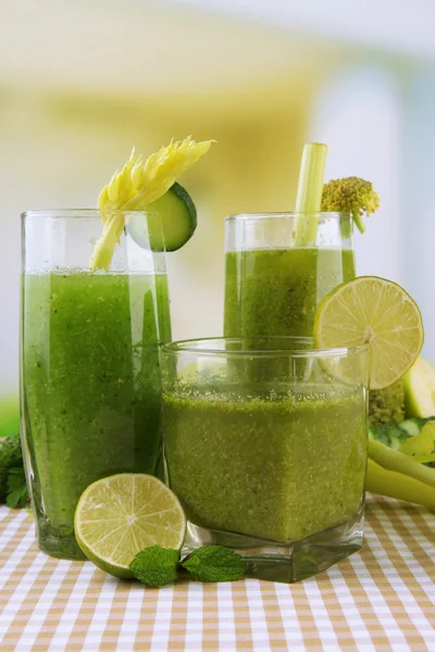 Glasses of green vegetable juice and vegetables on tablecloth on bright background — Stock Photo, Image